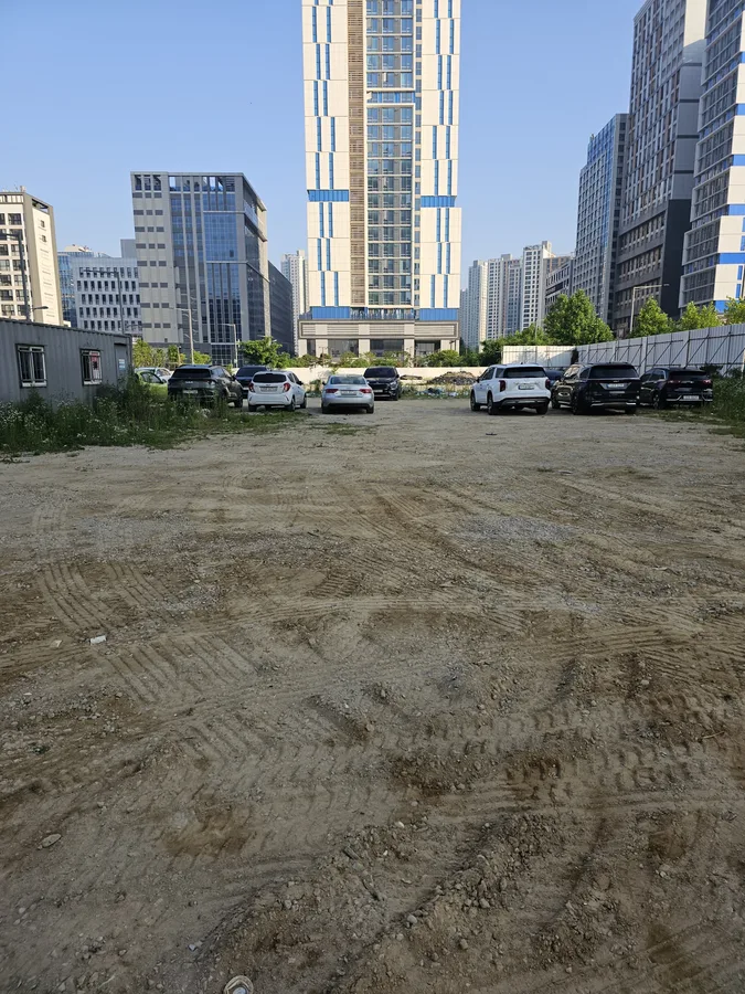 고르지 않은 흙바닥에 차량들이 각자 주차된 도심 공터 방문 전 전경