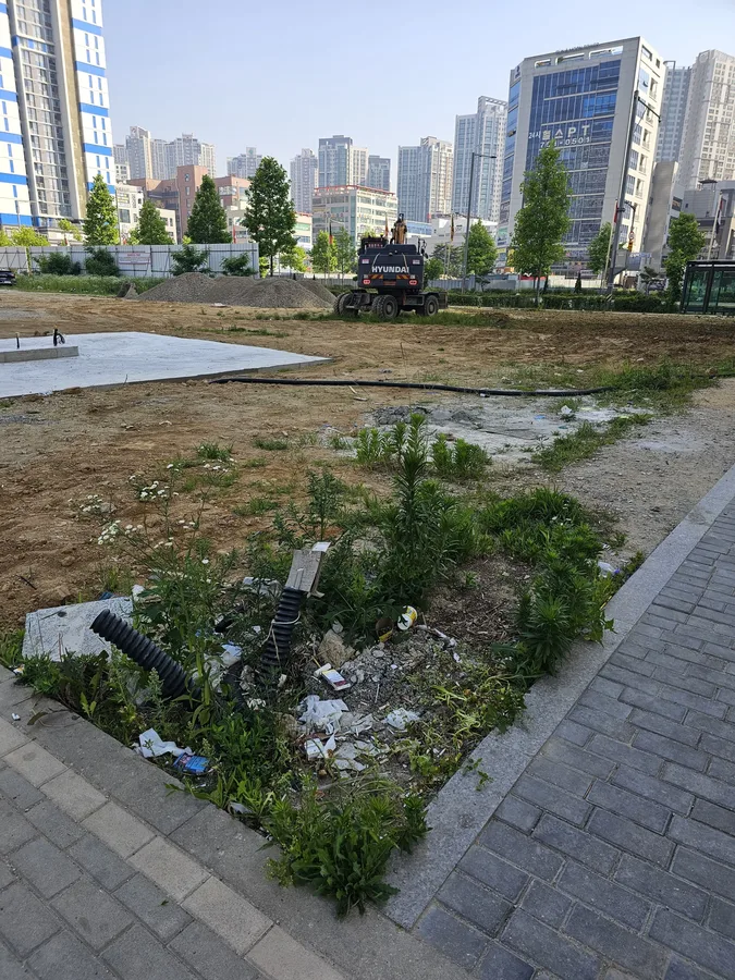 굴착기가 투입되어 도심 공터 바닥 정지작업을 시작하는 모습