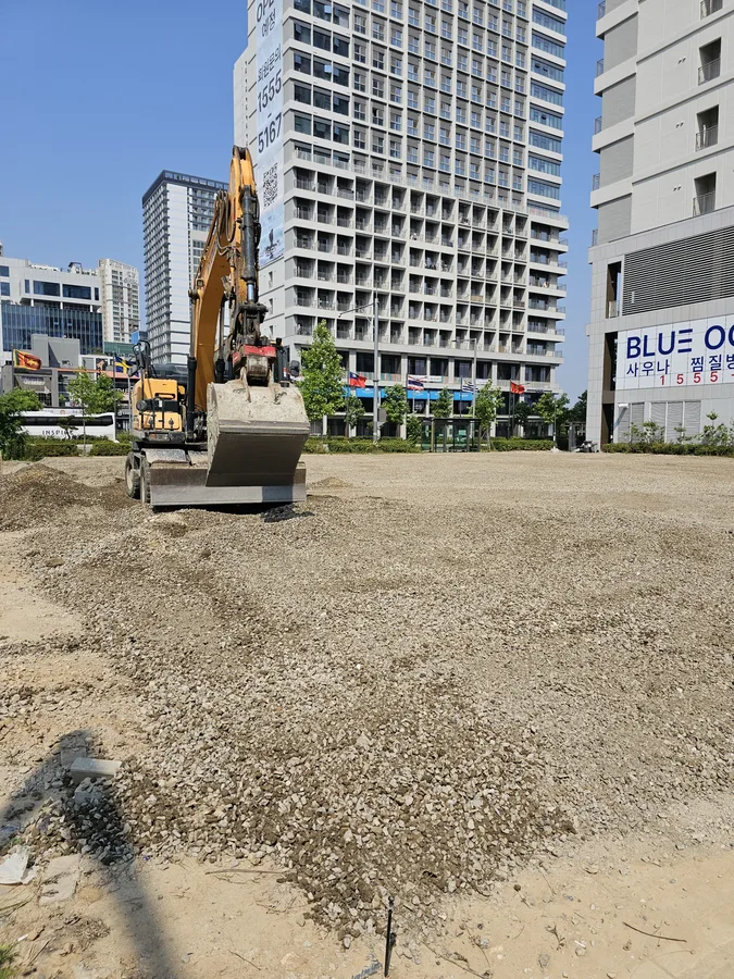 굴착 정지작업 후 잡석이 넓게 깔린 도심 공터 부지 전경